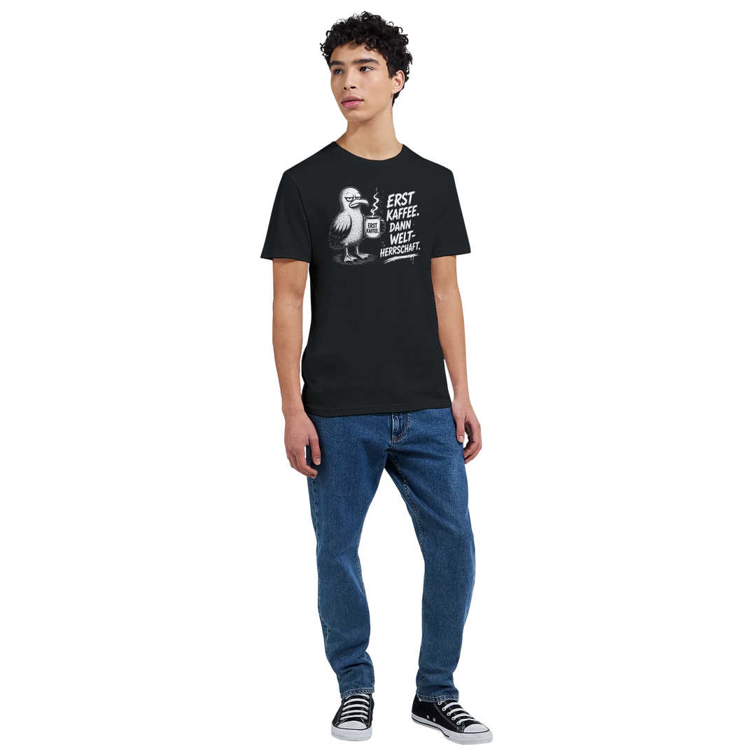 Ganzkörperansicht: junger Mann in schwarzem T-Shirt mit Möwen-Print, Jeans und Sneakers, Studio