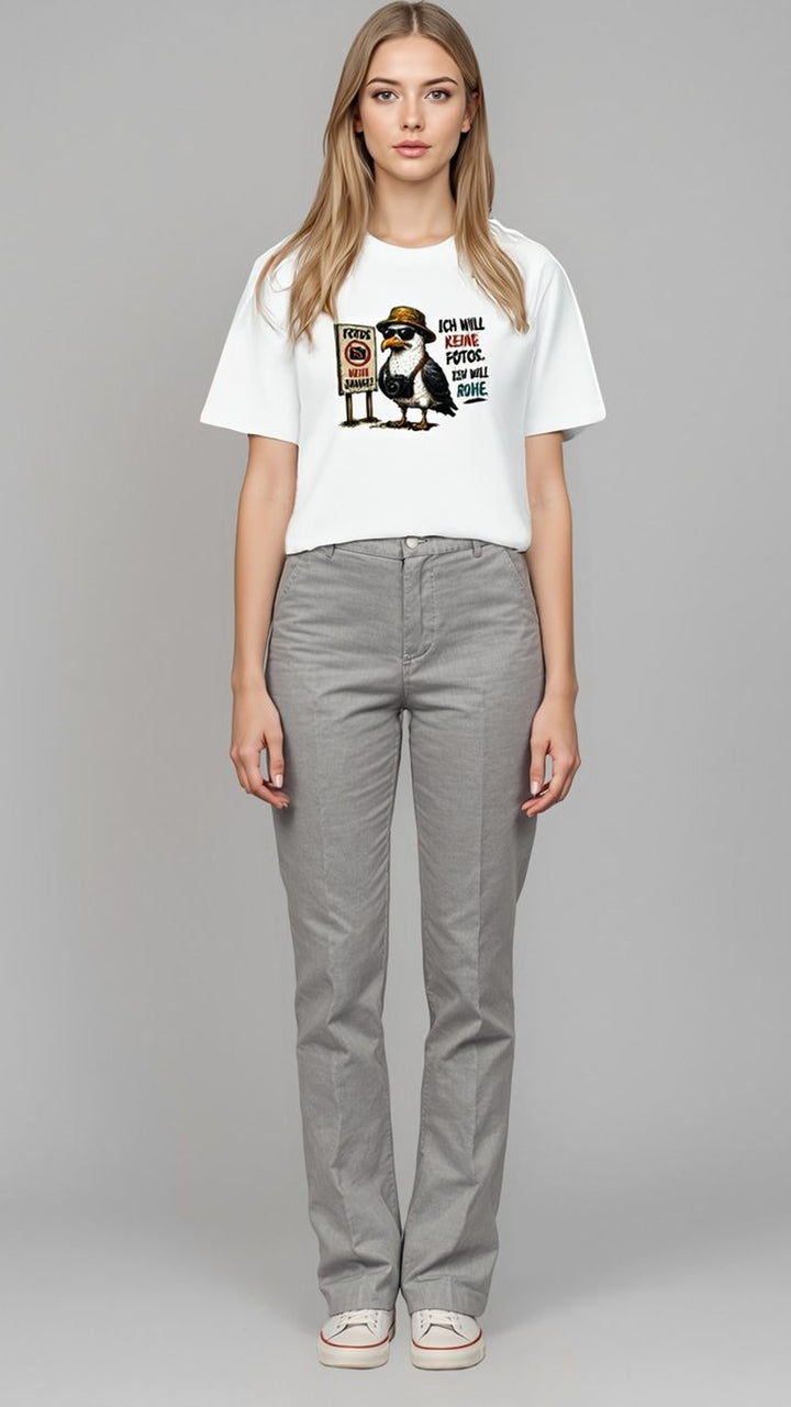 Frau in grauer Hose und weißem Oversized-Shirt mit Möwen-Motiv, Ganzkörperaufnahme vor grauem Hintergrund.