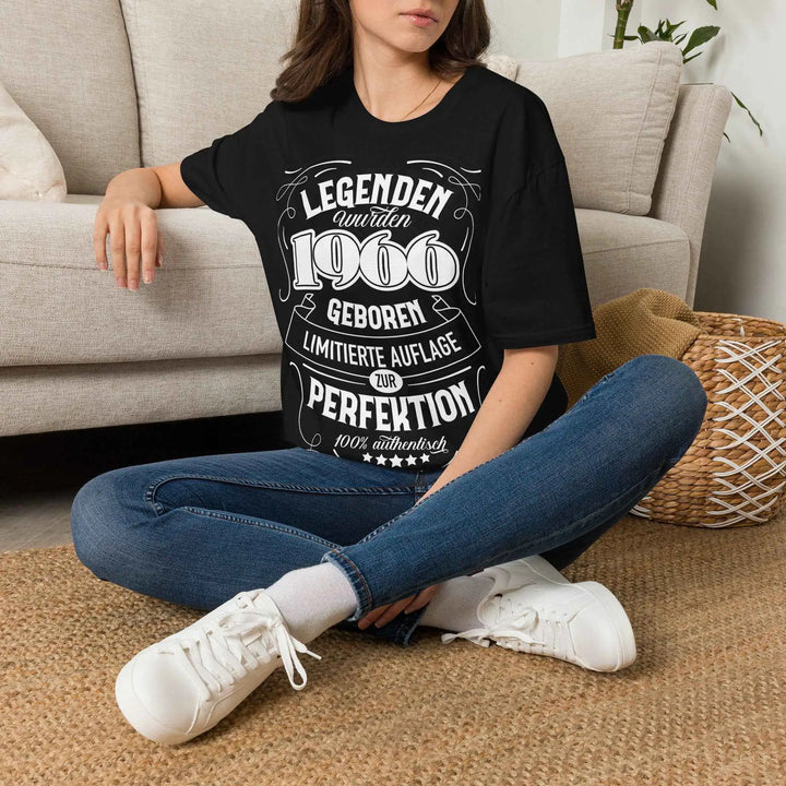 Frau sitzt im Schneidersitz auf einem Teppich vor dem Sofa, trägt schwarzes T-Shirt mit Print &