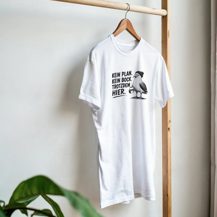 Weißes T-Shirt hängt an Holzkleiderständer, Zimmerpflanze im Vordergrund