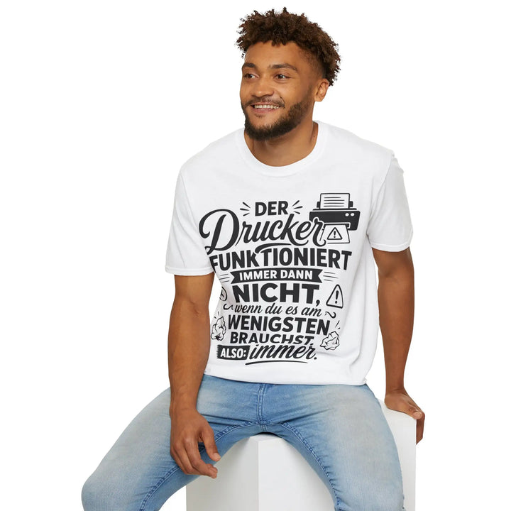 Lächelnder Mann sitzt auf einem weißen Würfel und blickt zur Seite, trägt das weiße Drucker-Statement-Shirt, Studiofoto.
