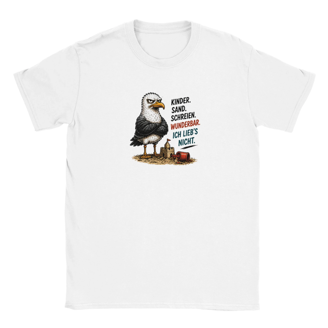 Flatlay des weißen T-Shirts mit grimmiger Möwe vor eingestürzter Sandburg und Spruch „Kinder. Sand. Schreien. Wunderbar.“
