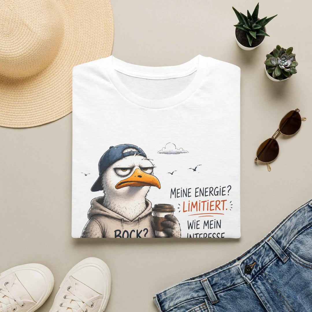 Weißes T-Shirt mit Möwen-Illustration und Spruch „Bock? Fehlanzeige.“ als Flatlay zwischen Sonnenhut, Sonnenbrille, Turnschuhen und Jeans.