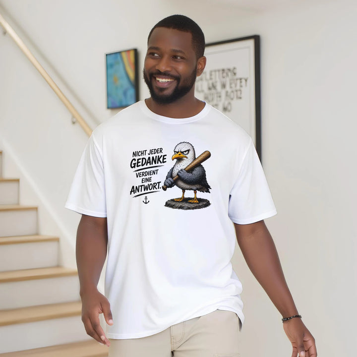 Lächelnder Mann im Oversize-T-Shirt mit Möwen-Print vor Treppenhaus zuhause.