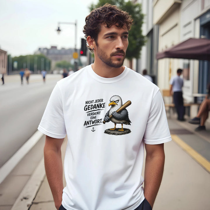 Mann mit lockigem Haar trägt das T-Shirt mit Möwen-Print auf einer Straße in der Stadt.