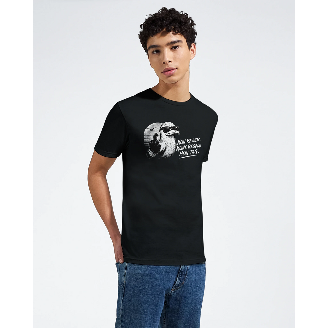 Nahaufnahme: junger Mann im schwarzen T-Shirt mit Möwen-Print vor hellem Studiohintergrund