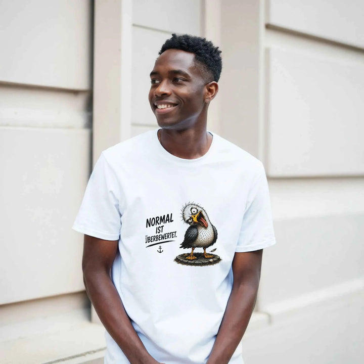 Lächelnder Mann lehnt in weißem Möwen-Shirt an einer Hauswand im Freien