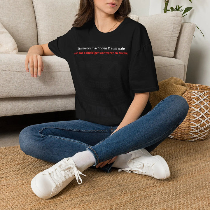Frau sitzt auf dem Boden und trägt schwarzes „Teamwork“-T-Shirt
