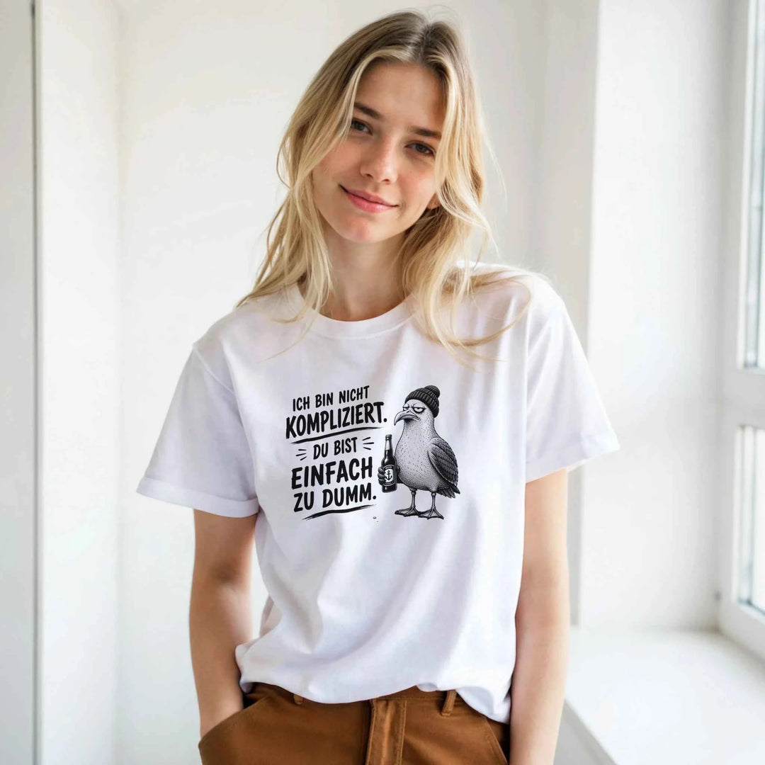 Frau trägt weißes T-Shirt mit Möwen-Print 'Ich bin nicht kompliziert. Du bist einfach zu dumm.' im Fensterlicht