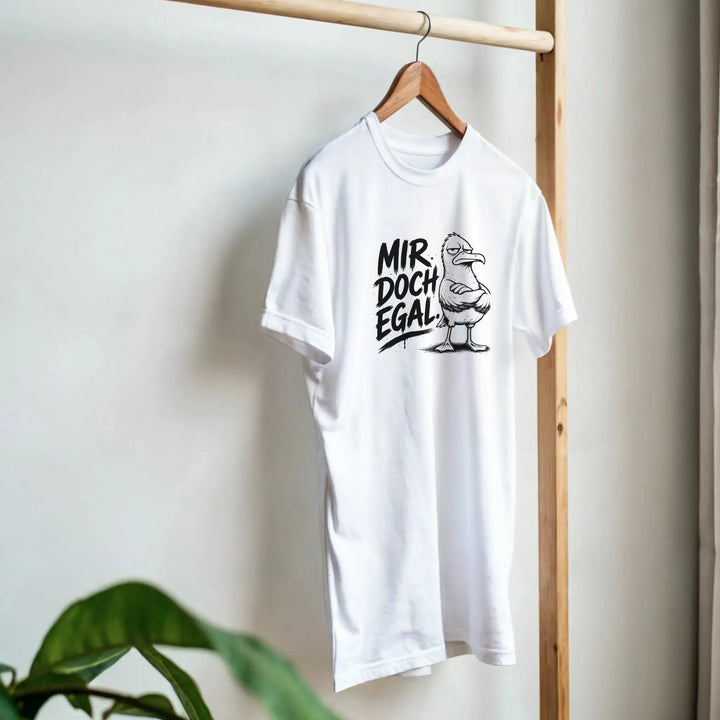 Weißes T-Shirt hängt an Holzkleiderständer, Zimmerpflanze im Vordergrund