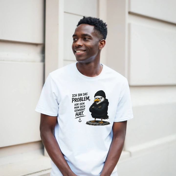 Lachender Mann lehnt im weißen T-Shirt an heller Hausfassade