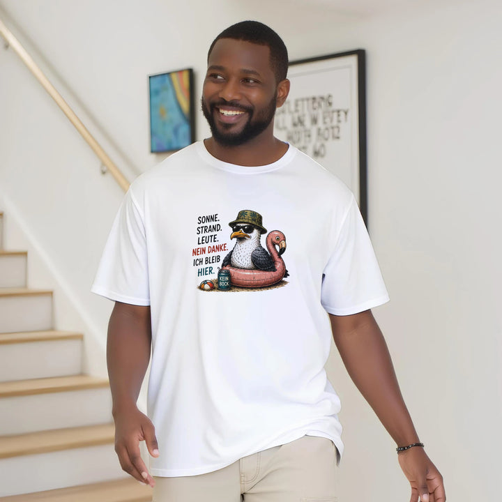 Lächelnder bärtiger Mann trägt das weiße Möwen-Shirt locker auf einem Treppenabsatz zu Hause.