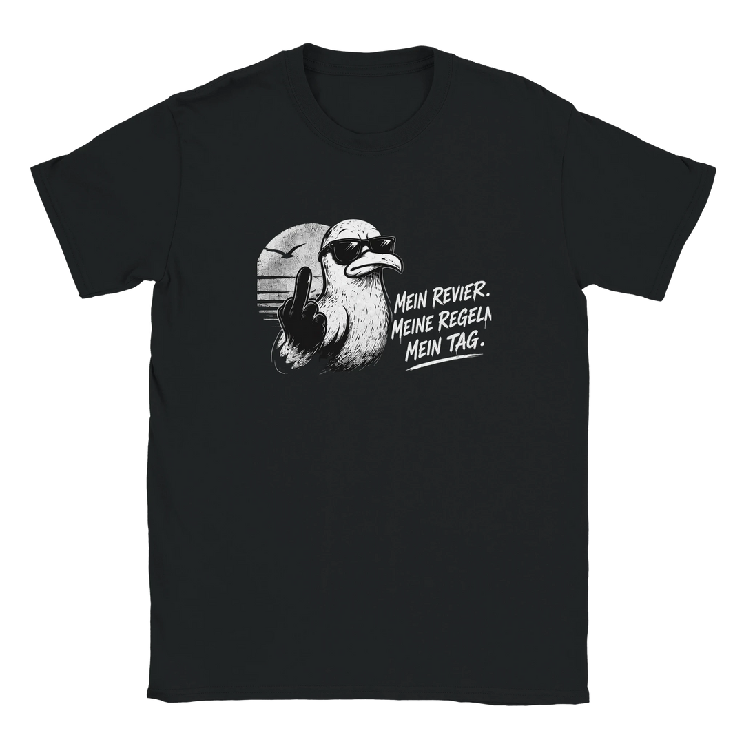 Flatlay des schwarzen T-Shirts mit Möwe im Sonnenuntergang und Spruch „Mein Revier. Meine Regeln. Mein Tag.“