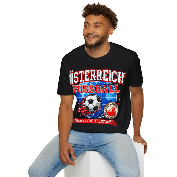 Lächelnder Mann sitzt und trägt schwarzes Shirt mit Österreich-Fussball-Aufdruck