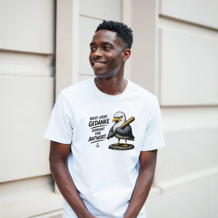 Lächelnder Mann im T-Shirt mit Möwen-Print vor heller Hauswand.
