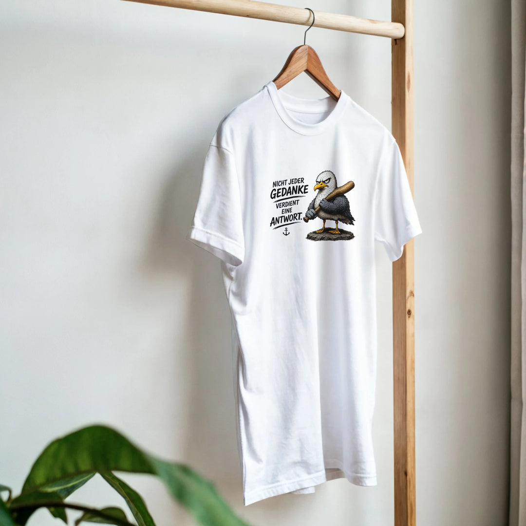 T-Shirt mit Möwen-Print hängt auf Holzständer, im Vordergrund eine Zimmerpflanze.