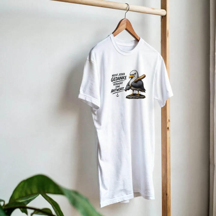 T-Shirt mit Möwen-Print hängt auf Holzständer, im Vordergrund eine Zimmerpflanze.