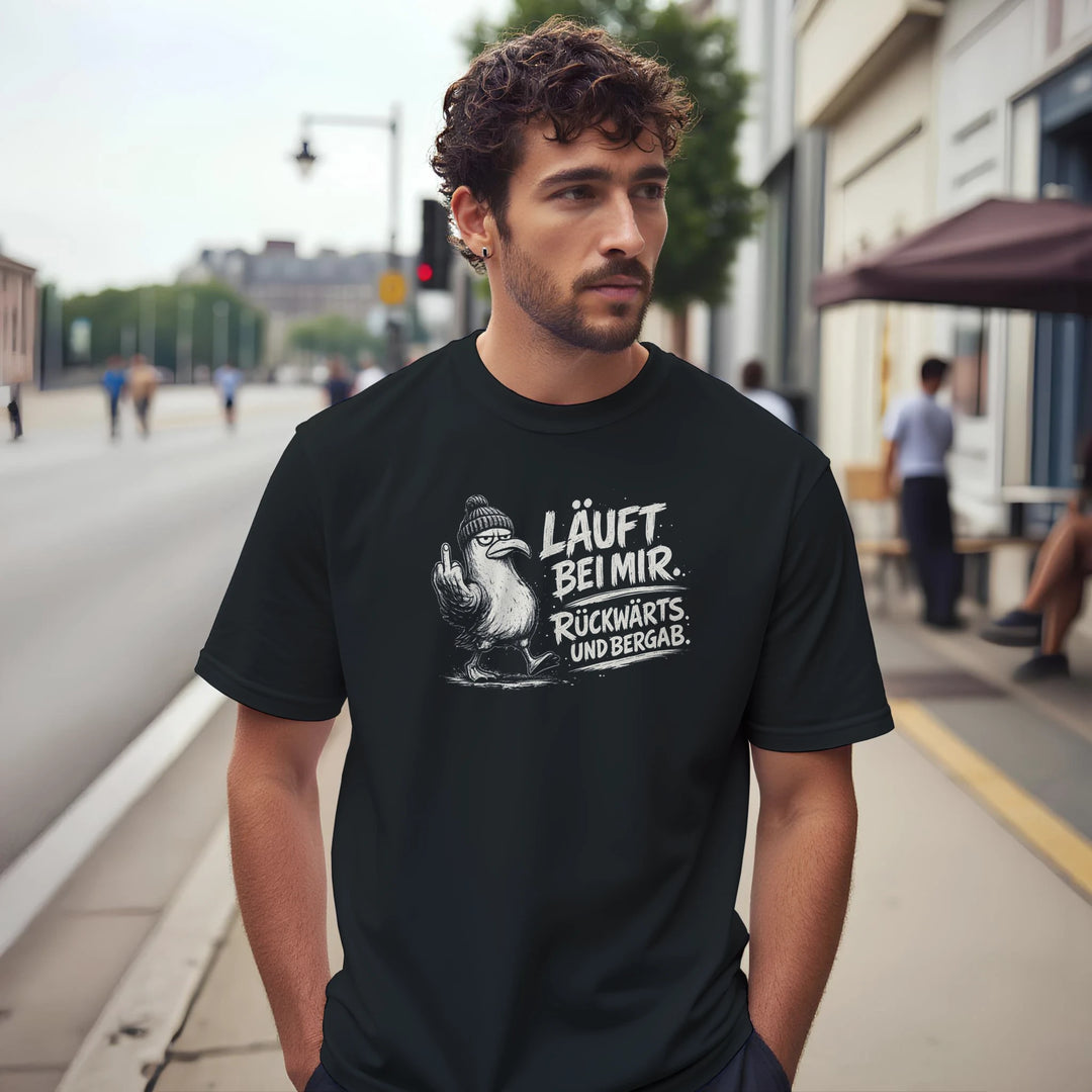 Bärtiger Mann trägt das schwarze Möwen-Shirt auf einer belebten Stadtstraße mit unscharfem Hintergrund.