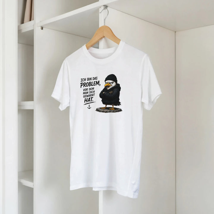 T-Shirt mit Vogel-Motiv hängt am Kleiderbügel im offenen Kleiderschrank