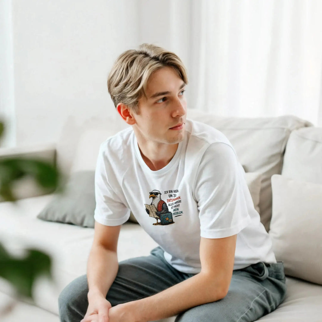 Junger Mann sitzt entspannt auf dem Sofa im weißen Oversized-Shirt mit Möwen-Motiv.