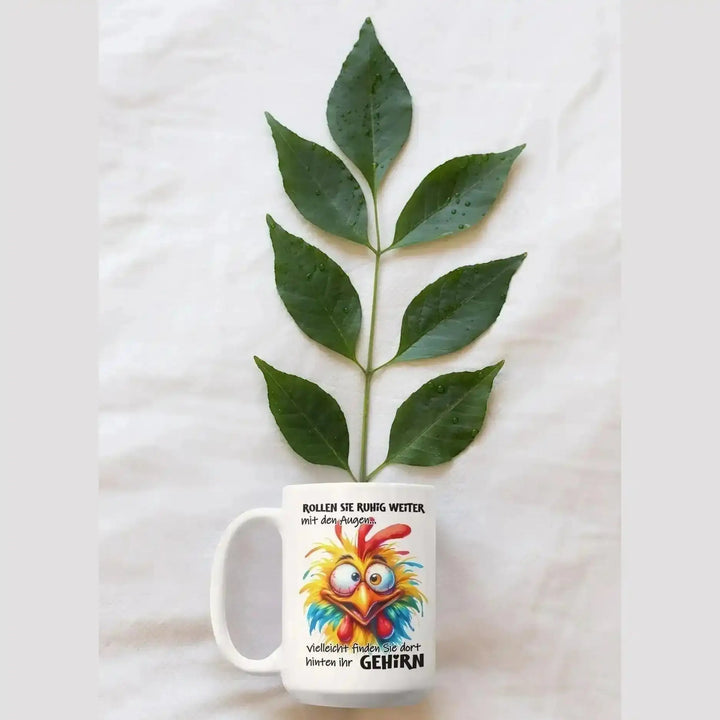 Augenrollen-Tasse als Flatlay-Foto mit einem grünen Blätterzweig, der wie eine Pflanze aus der Tasse ragt