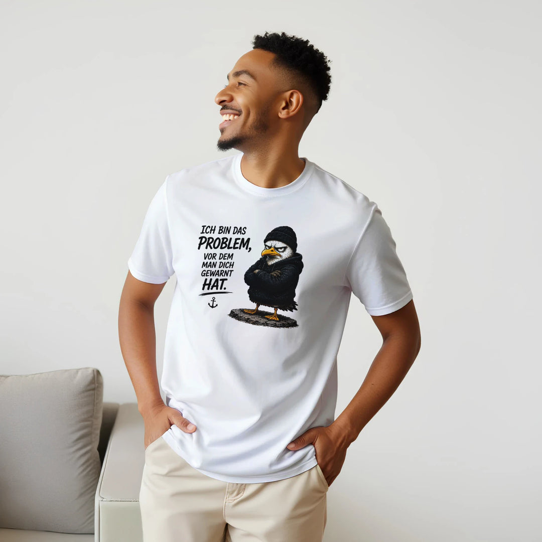 Lachender Mann im weißen T-Shirt steht neben grauem Sofa im Wohnzimmer