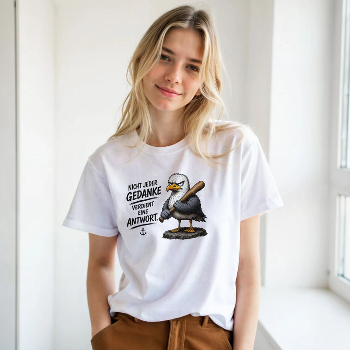 Frau am Fenster trägt weißes T-Shirt mit Möwen-Motiv zu brauner Hose.