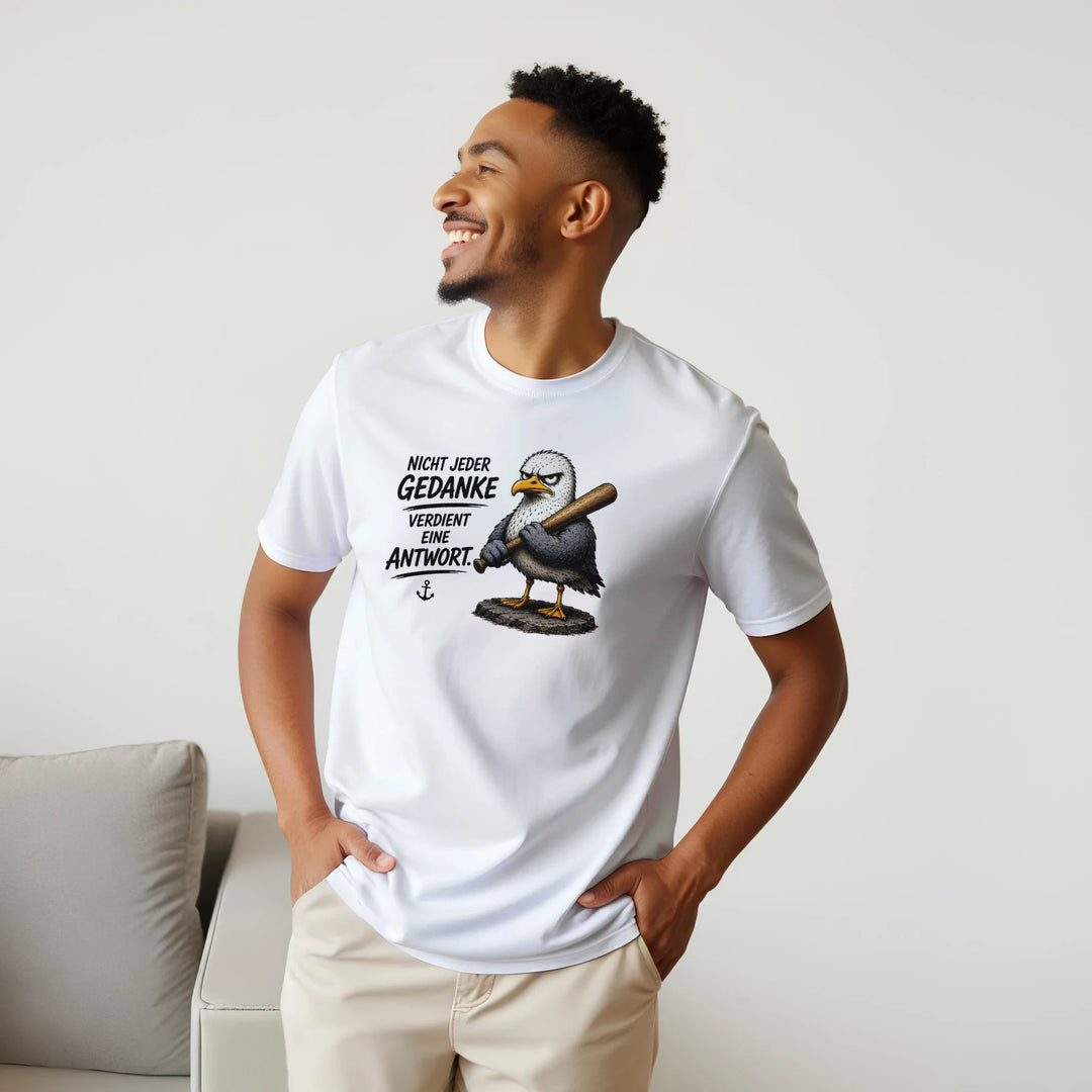 Lachender Mann im Profil trägt das T-Shirt mit Möwen-Motiv neben einer Couch.