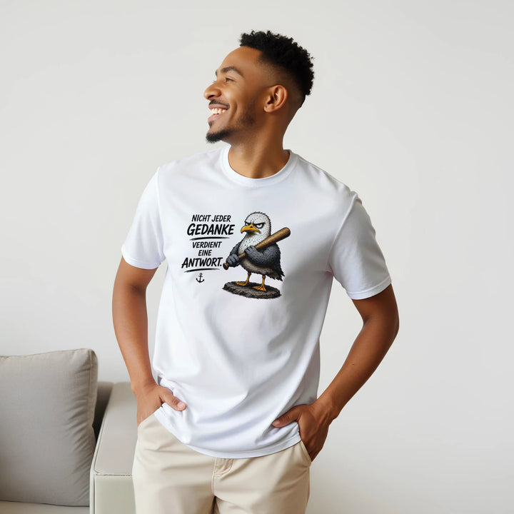 Lachender Mann im Profil trägt das T-Shirt mit Möwen-Motiv neben einer Couch.