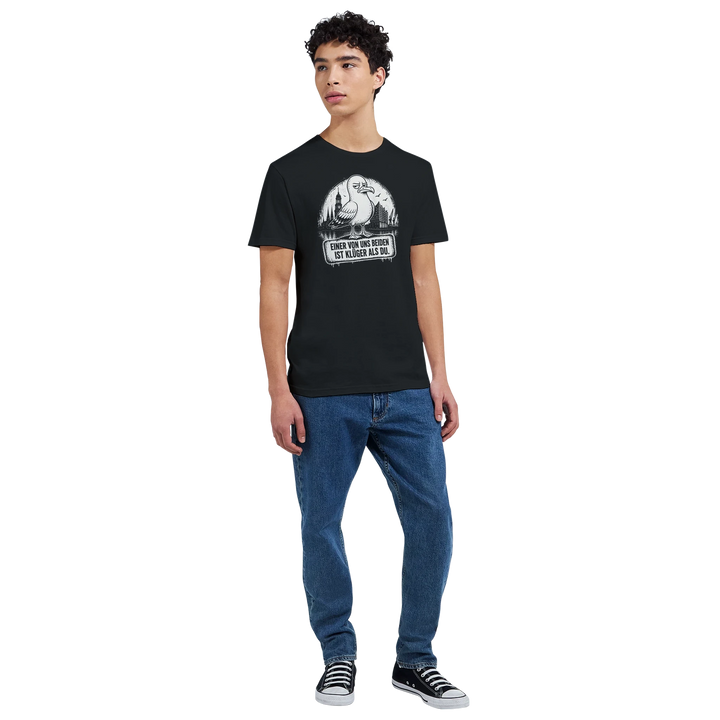 Ganzkörperansicht: Mann im schwarzen T-Shirt mit Möwe und Hamburg-Skyline, kombiniert mit Jeans und Sneakern.