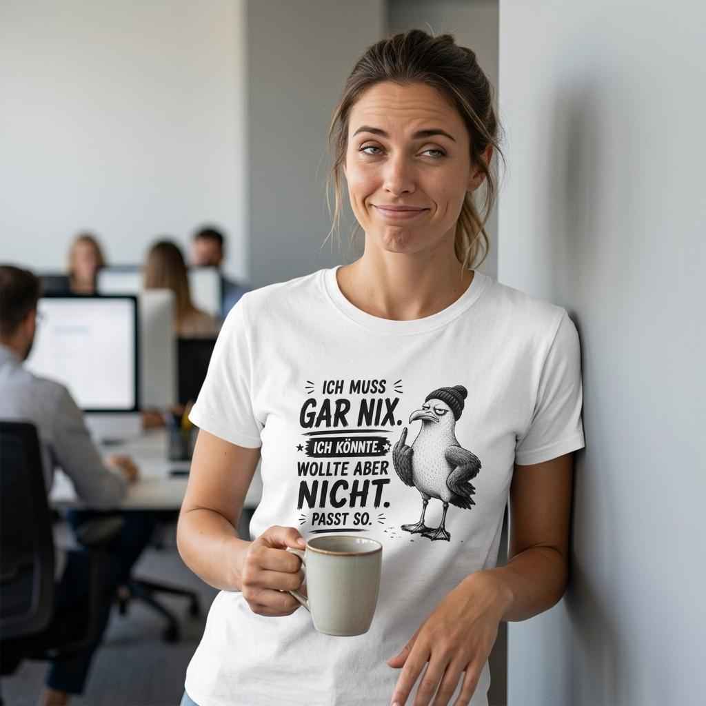Frau im Büro trägt weißes T-Shirt mit Möwen-Spruch 'Ich muss gar nix. Passt so.' und hält eine Kaffeetasse