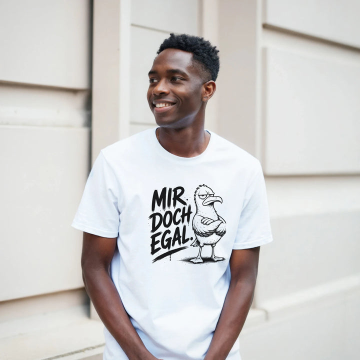 Lächelnder Mann lehnt an heller Hausfassade, weißes T-Shirt mit Möwen-Motiv