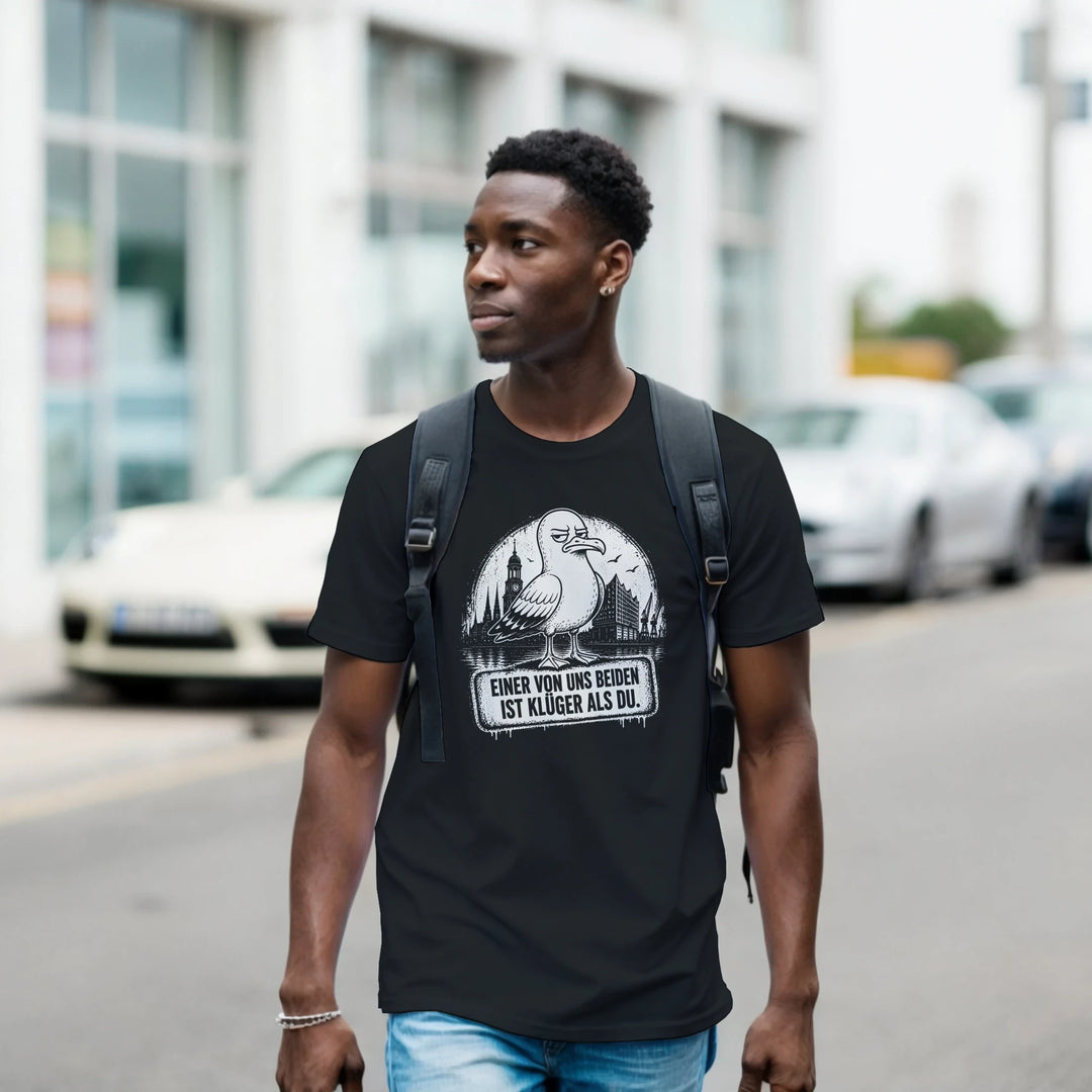 Mann mit Rucksack trägt das T-Shirt mit Hamburg-Möwe beim Spaziergang durch die Stadt, Autos im Hintergrund.