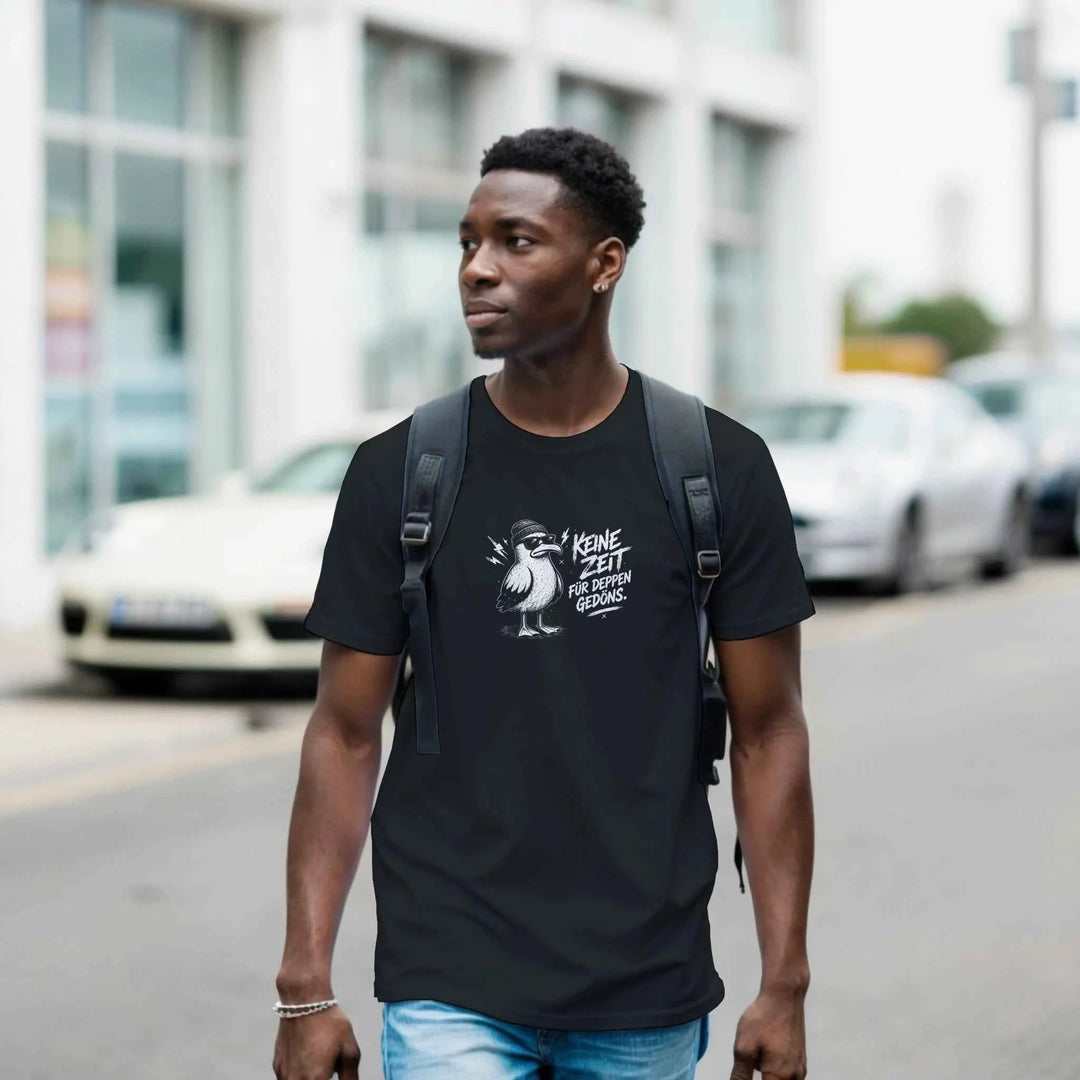 Mann mit Rucksack geht durch die Stadt, schwarzes T-Shirt mit Möwe in Beanie und Sonnenbrille und Spruch „Keine Zeit für Deppen-Gedöns.“
