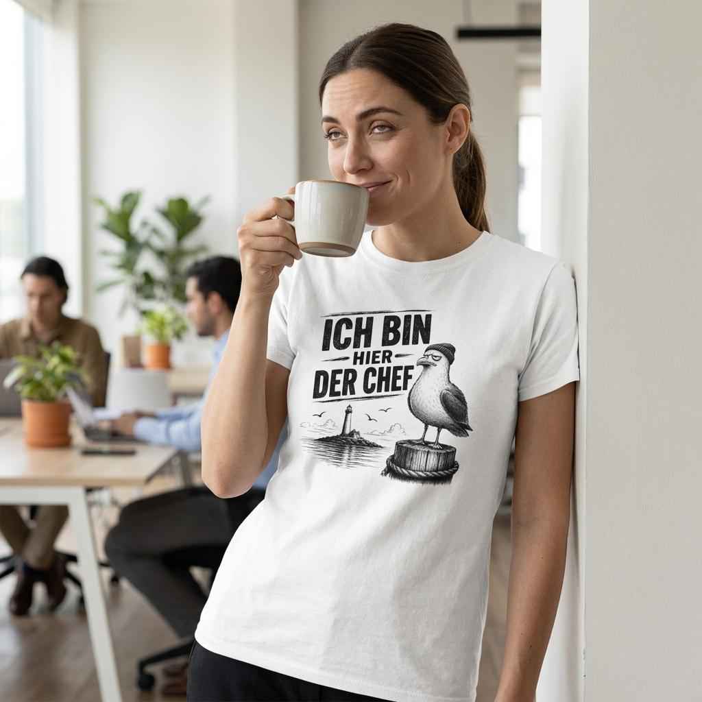 Frau im Büro trinkt Kaffee in weißem T-Shirt mit Möwen-Motiv 'Ich bin hier der Chef' und Leuchtturm