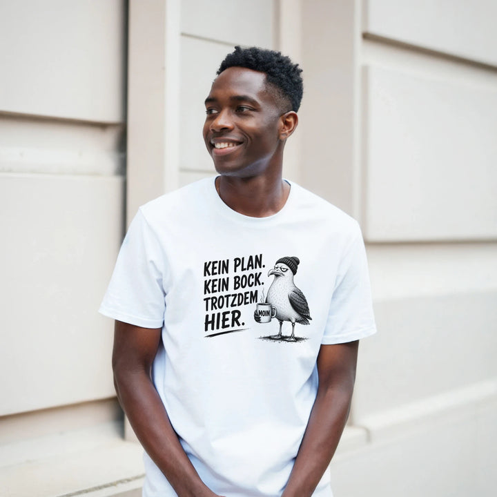 Lächelnder Mann lehnt an heller Hausfassade, weißes T-Shirt mit Möwen-Print