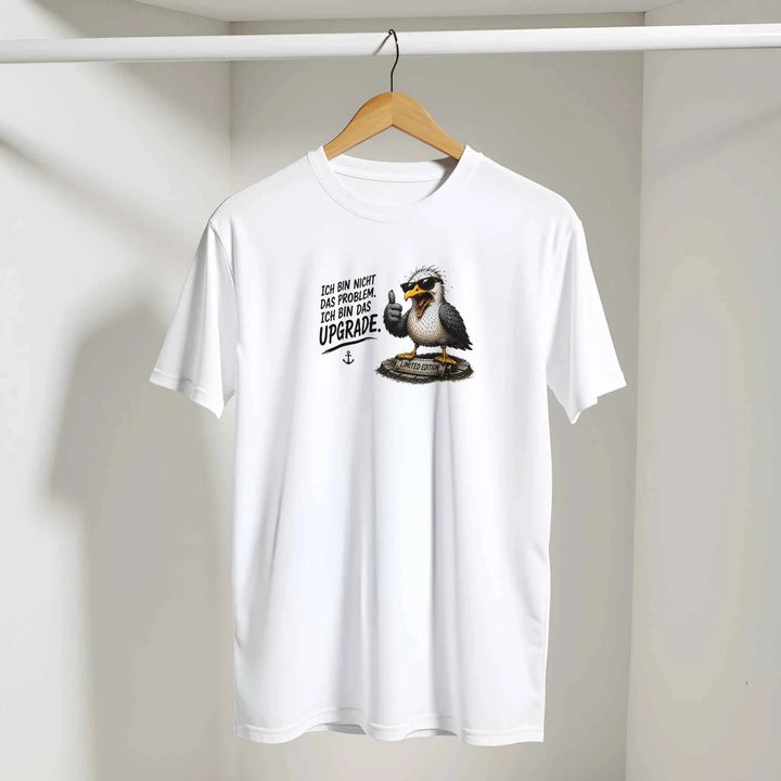 Weißes T-Shirt mit Möwen-Print auf einem Kleiderbügel vor heller Wand hängend