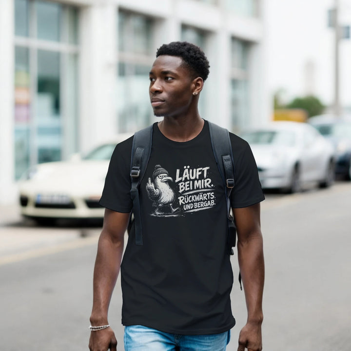 Mann mit Rucksack trägt das schwarze Möwen-Shirt beim Spaziergang durch die Stadt, Autos im Hintergrund.