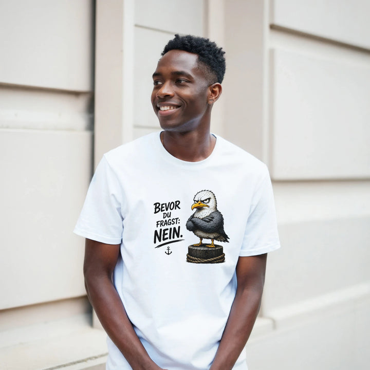 Lachender Mann lehnt im weißen T-Shirt an heller Hausfassade