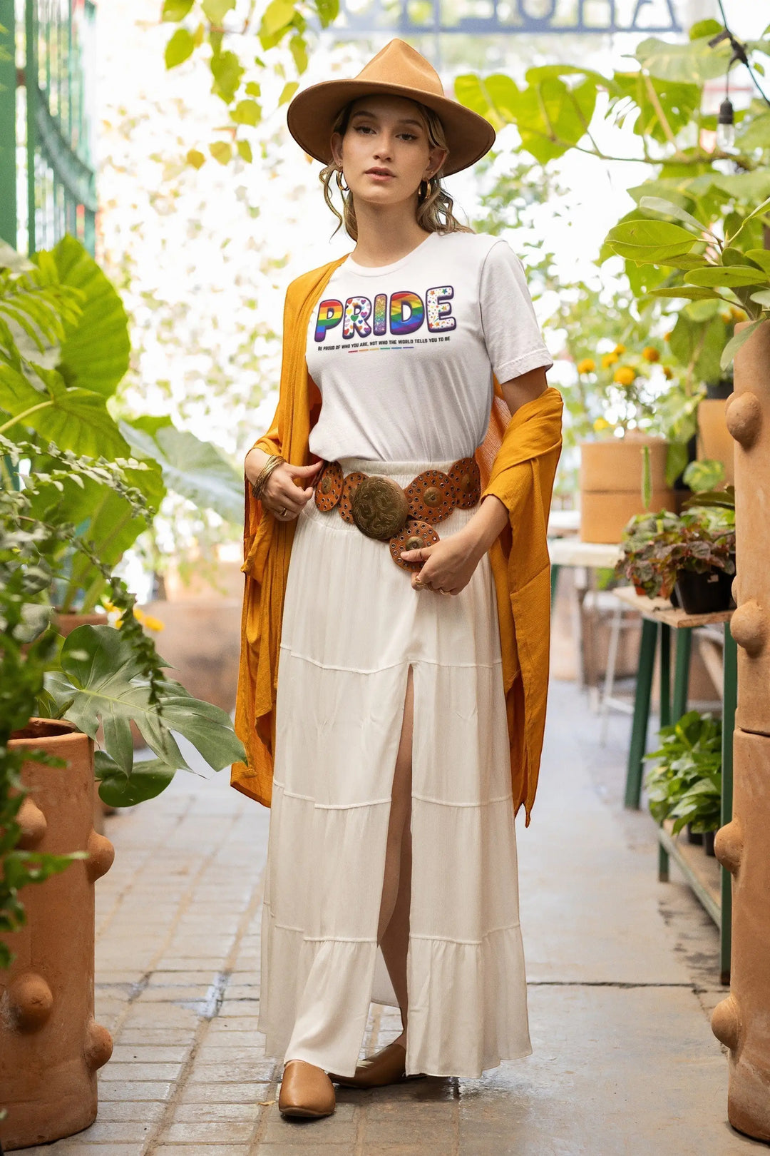 KlareAnsage Pride T-Shirt aus Baumwolle mit buntem Regenbogen-Schriftzug, getragen von einer Frau mit Hut im Garten