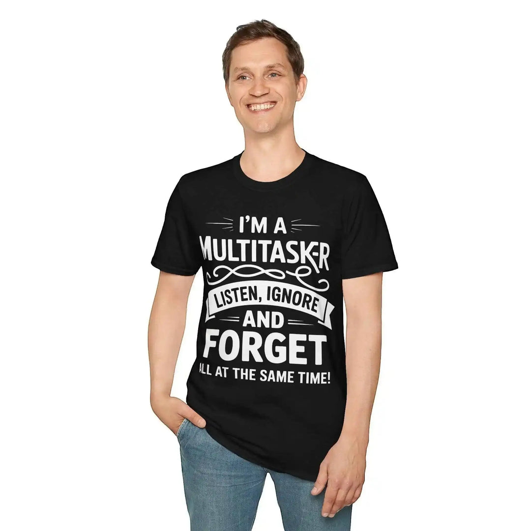 Lächelnder Mann steht mit einer Hand in der Hosentasche und trägt das schwarze Multitasker-Shirt vor weißem Hintergrund.