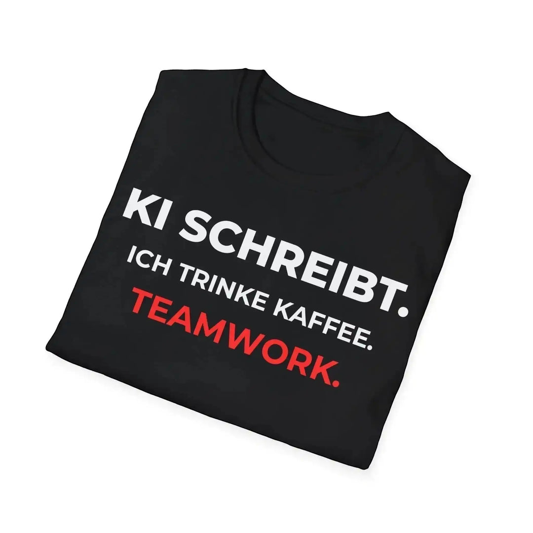 Schwarzes T-Shirt mit Spruch „KI schreibt. Ich trinke Kaffee. Teamwork.“, diagonal gefaltet fotografiert