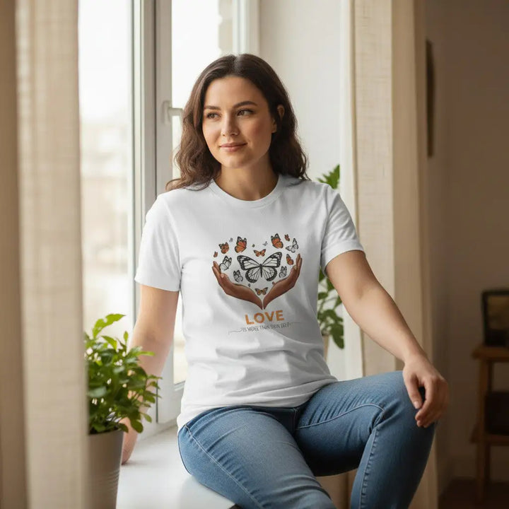 KlareAnsage T-Shirt in Weiss mit Schmetterling-Herz-Motiv, getragen von einer Frau am Fenster.