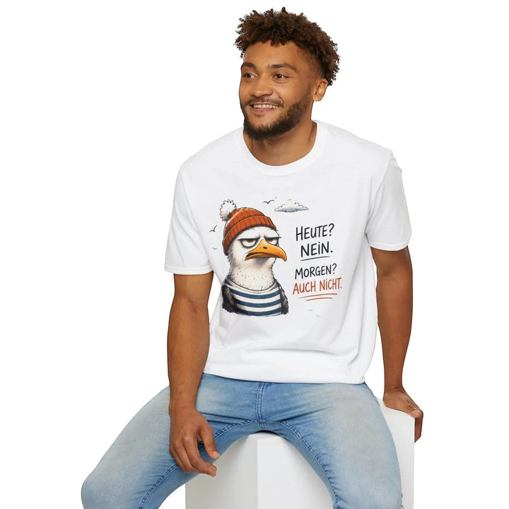 Lächelnder Mann sitzt auf einem weißen Würfel und blickt zur Seite, trägt das weiße Möwen-Shirt, Studiofoto.